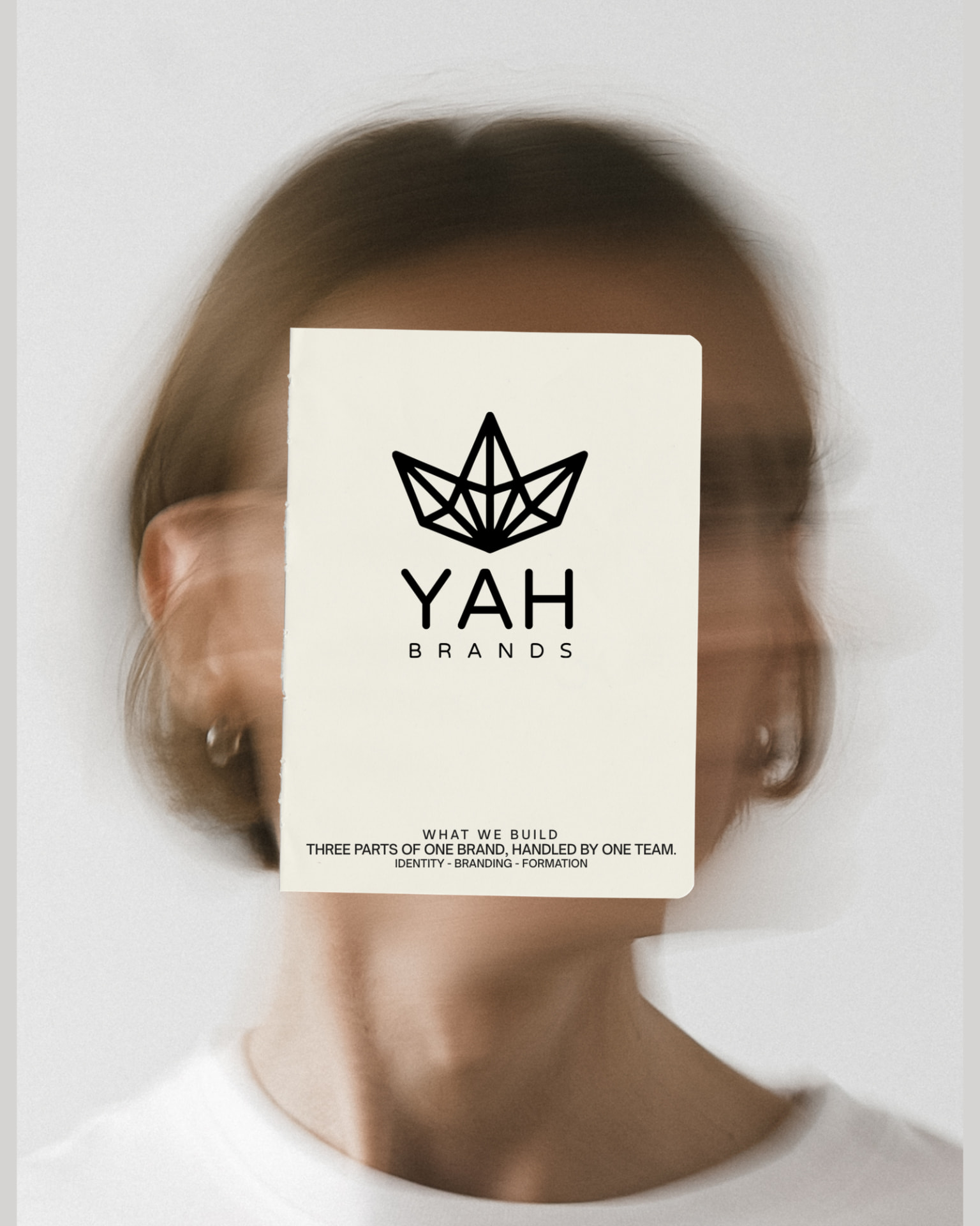 YaH Brands What We Build campaign featuring the crown mark on a card held in front of a portrait