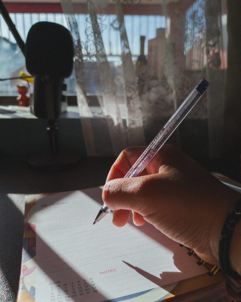 Hand writing in a planner by a sunlit window